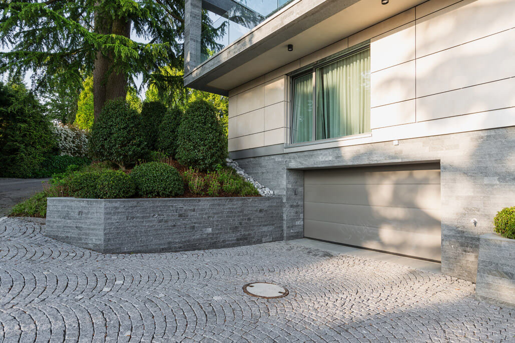 Eine Fassade aus Naturstein mit kubischer Terrassenüberdachung