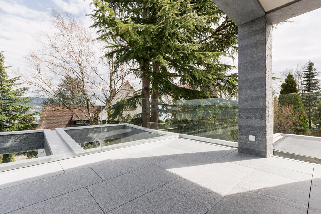 Eine Fassade aus Naturstein mit kubischer Terrassenüberdachung