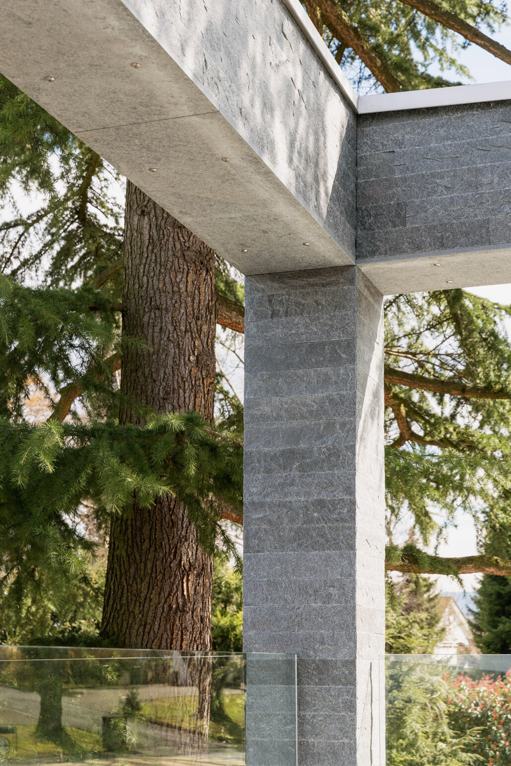 Eine Fassade aus Naturstein mit kubischer Terrassenüberdachung