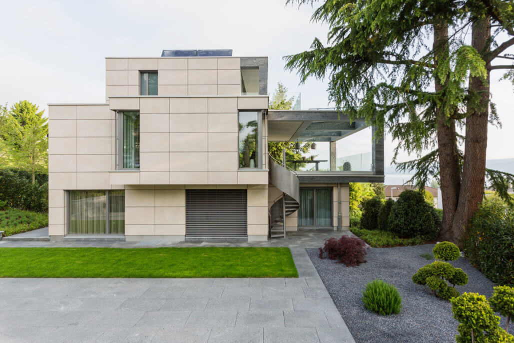 Eine Fassade aus Naturstein mit kubischer Terrassenüberdachung