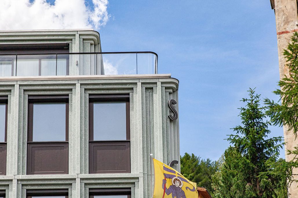 Eine Fassade aus Naturstein mit kubischer Terrassenüberdachung