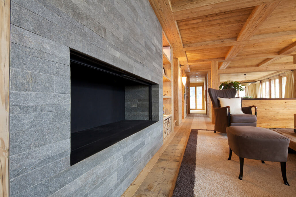Cheminéeverkleidung in Naturstein in modernem Chalet